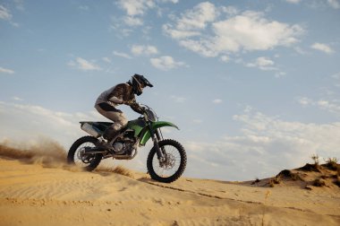 Profesyonel motokros binicisi kum tepesinden kayıyor