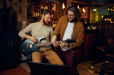 Müzisyen erkek öğrenci gitar çalmayı öğretiyor