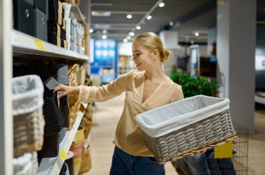 Hasır sepeti alan kadın dükkânda duruyor.