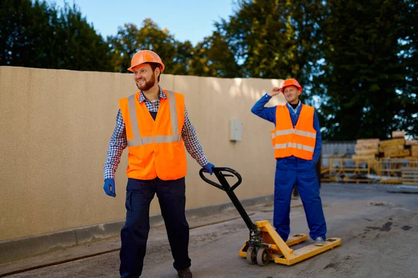 Travailleur constructeur utilisant un camion à palettes chargeur à main — Photo