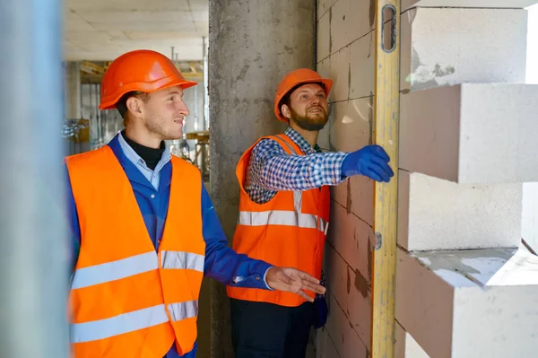 Constructeurs de maçons vérifiant le niveau du mur avec l'outil — Photo