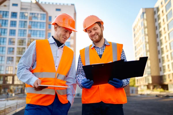 Zwei lächelnde Bauarbeiter diskutieren Grundriss — Stockfoto