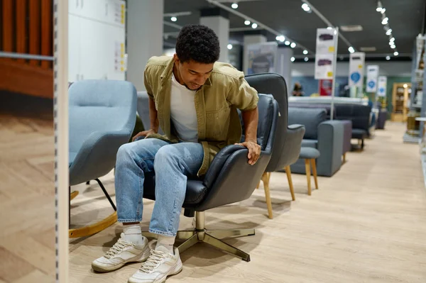 Νεαρός διαλέγει καρέκλα σε κατάστημα επίπλων — Φωτογραφία Αρχείου