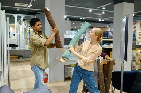 Cheerful couple fighting with cushion in store — ストック写真