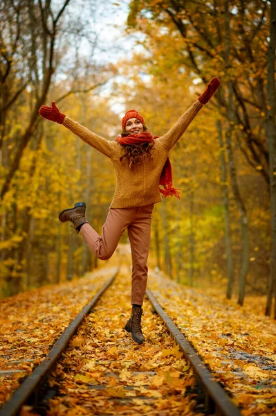 Woman jumping over railroad in autumn forest — Stock Photo, Image