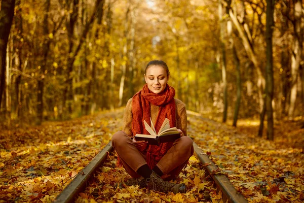 Woman reading book while sitting railroad track — Foto Stock