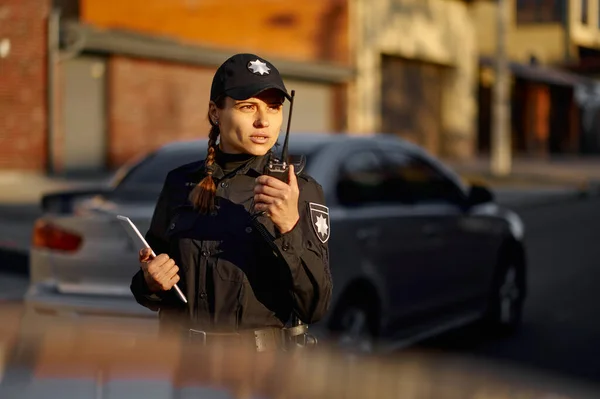 Police woman talking using walkie-talkie during patrolling — Zdjęcie stockowe