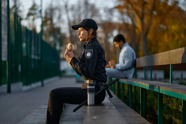 Police woman take break eating in park — Stockfoto