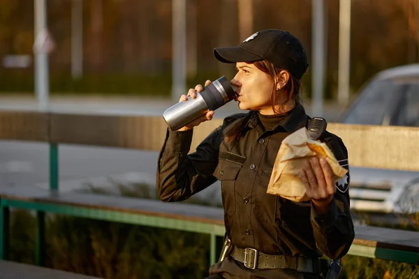 Police woman take break eating in park — Stockfoto
