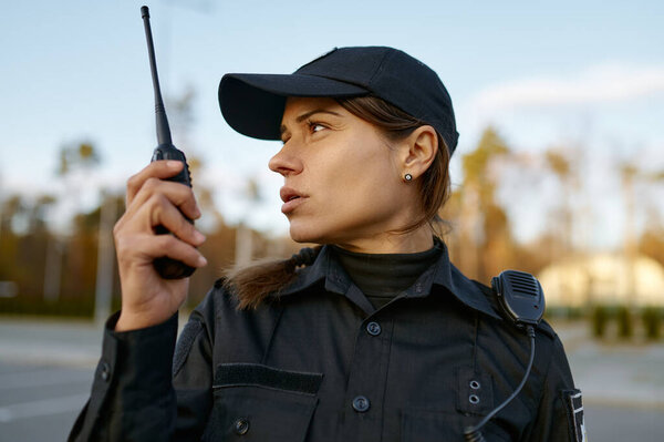 Portrait of female cop communicating on walkie-talkie