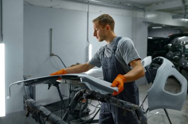 Man painter looking at finished car body