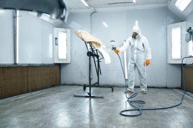 Repairman with airbrush pulverizer painting car door