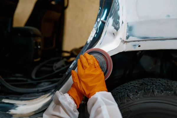 Auto painter polishing plastered car body part — Stock Photo, Image