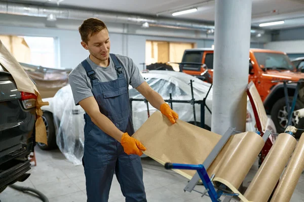 Car repair service workman taking wrapping paper — Stockfoto