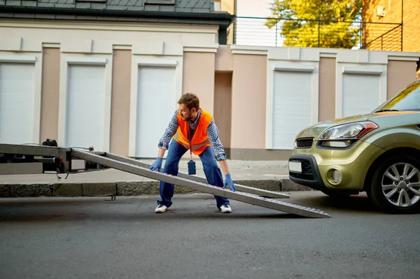 Worker preparing tow truck platform for car — Stockfoto