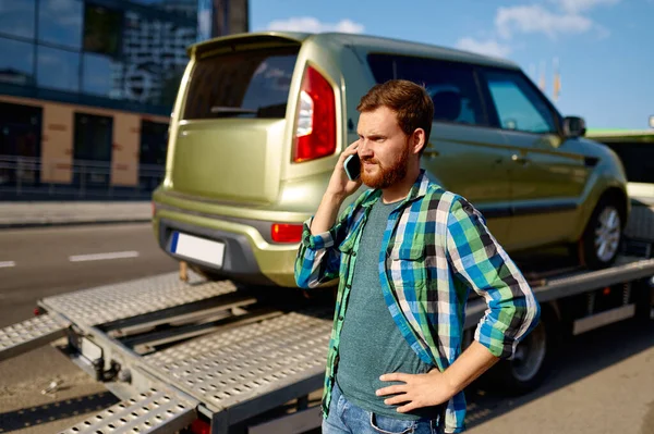 Mann ruft an, während Abschleppwagen Auto aufnimmt — Stockfoto