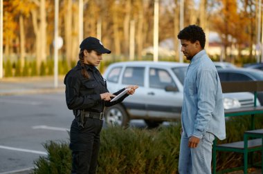 Kadın polis, yoldan geçen erkeklerin kimlik belgelerini kontrol ediyor.