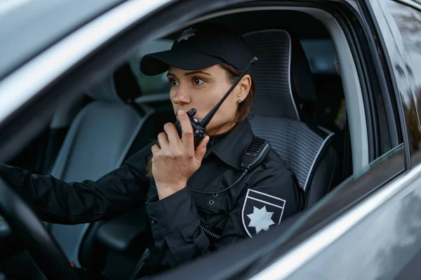 Mujer policía usando la calle patrulla de radio en el coche — Foto de Stock