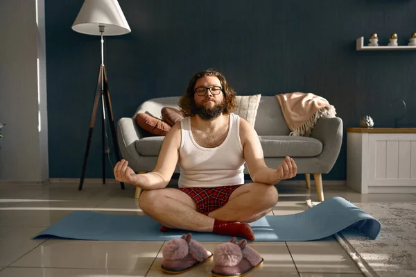 Hombre graso divertido meditando practicando yoga en casa — Foto de Stock