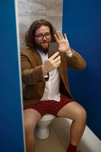 Businessman talking phone while sitting on toilet — Stock Photo, Image