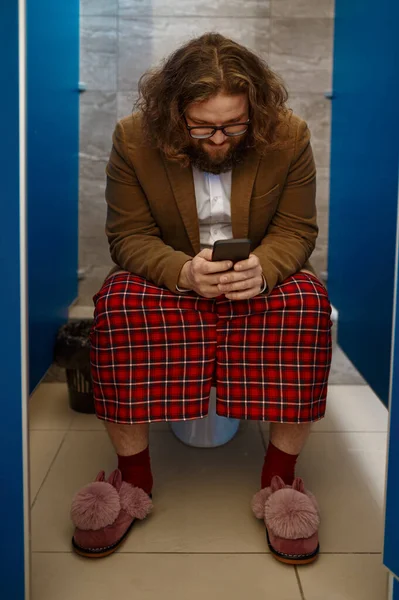 Podnikatel pomocí svého telefonu, zatímco sedí na záchodě — Stock fotografie