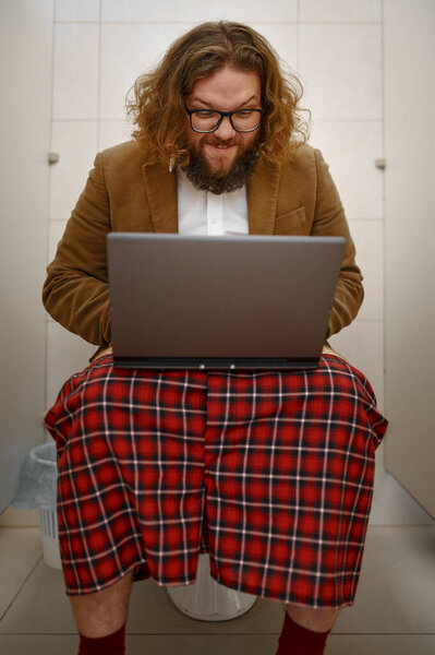 Странный бизнесмен работает с ноутбуком в туалете
