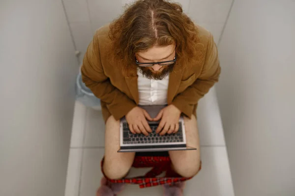 Freelance zakenman werkt laptop in het toilet — Stockfoto