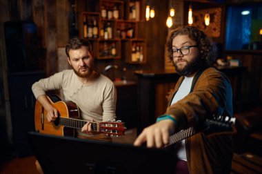 Öğretmen genç adama gitar dersi veriyor.