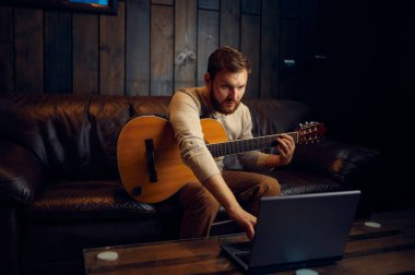 Genç adam internet üzerinden gitar çalmayı öğreniyor