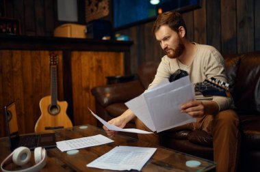 Genç gitarist müzik notaları öğreniyor.