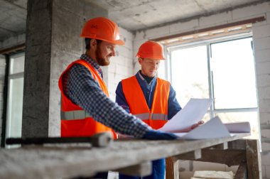 Dairesinde bina planı olan inşaat işçisi.