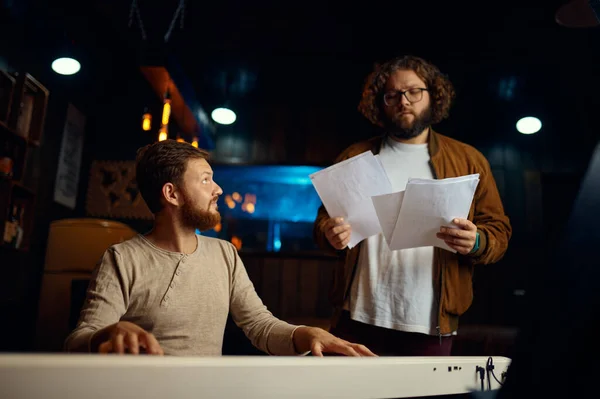 Tutor checking notes while student playing piano — Stock Photo, Image