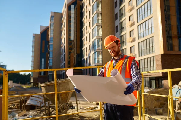 Builder or engineer holding blueprint standing outside — Stock Photo, Image