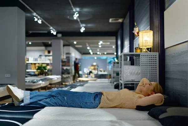 Woman choosing bed mattress in furniture store — Stockfoto