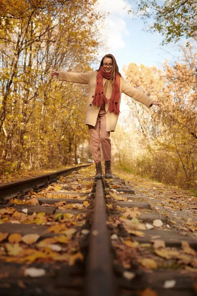 Vrouw balanceert op spoorweg over herfst achtergrond — Stockfoto