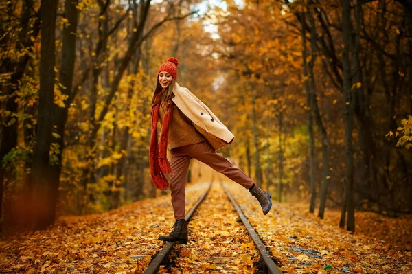 Woman jumping over railroad in autumn forest — Stockfoto
