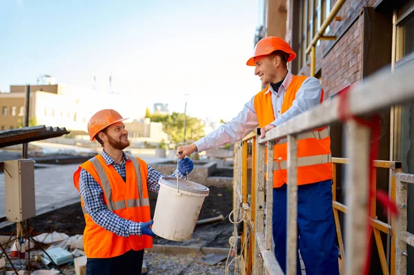 Budowniczowie pomagają sobie na placu budowy — Zdjęcie stockowe