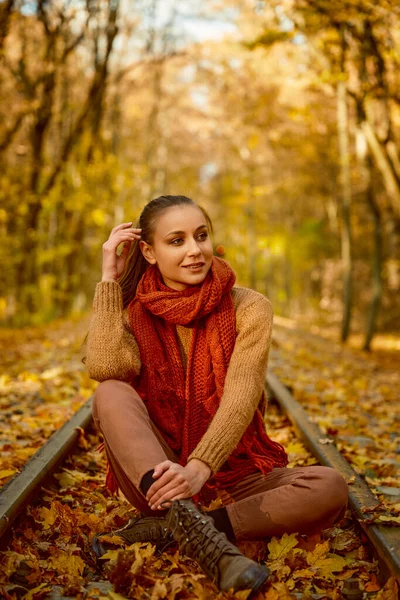 Tren yolunda oturmuş kitap okuyan bir kadın.