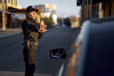 Trafik kontrolü için telsiz kullanan bir kadın polis.