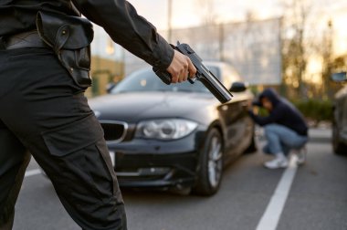 Kadın polis araba hırsızının özgeçmişine silah doğrultuyor.