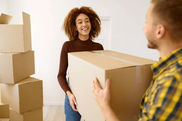 Happy multiethnic couple carrying cardboard box together — Stock Photo, Image