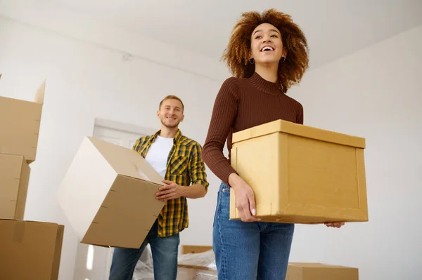 Feliz pareja multiétnica llevando caja de cartón juntos — Foto de Stock