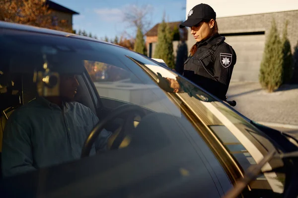Jeune policière avec tablette debout près de la voiture — Photo