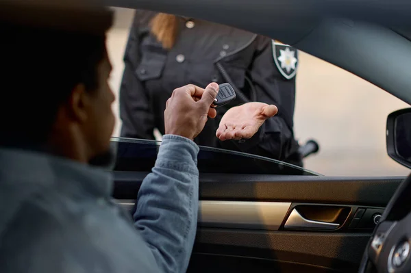 Fechar motorista de carro dando a chave para a policial — Fotografia de Stock