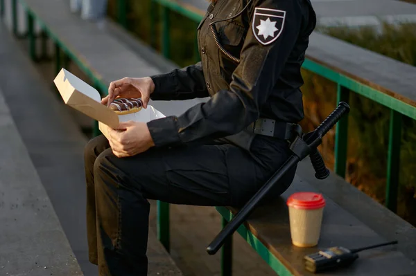 Policjant jedzący pączki w parku zbliżenie — Zdjęcie stockowe