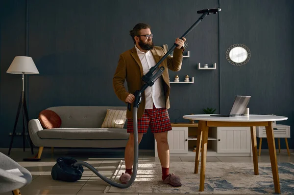 Glad multitasking businessman vacuum uming and working online — стоковое фото