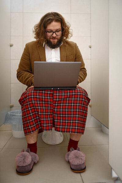 Внештатный бизнесмен работает с ноутбуком в туалете