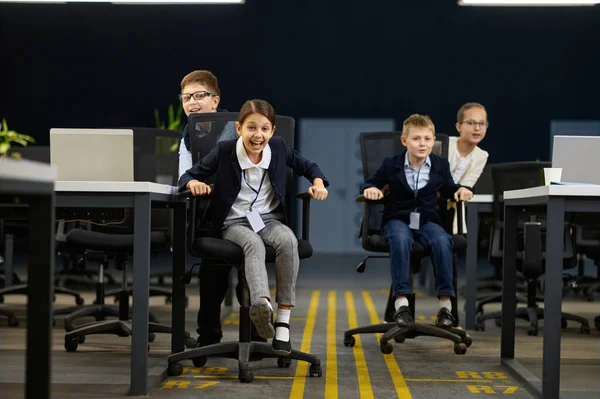 Ділові діти весело катаються на офісному стільці — стокове фото