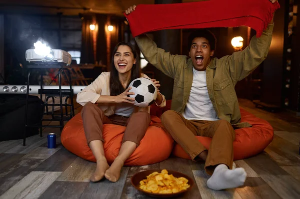 Couple regardant match de football sur le projecteur à domicile — Photo