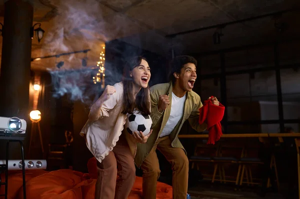 Couple regardant match de football sur le projecteur à domicile — Photo